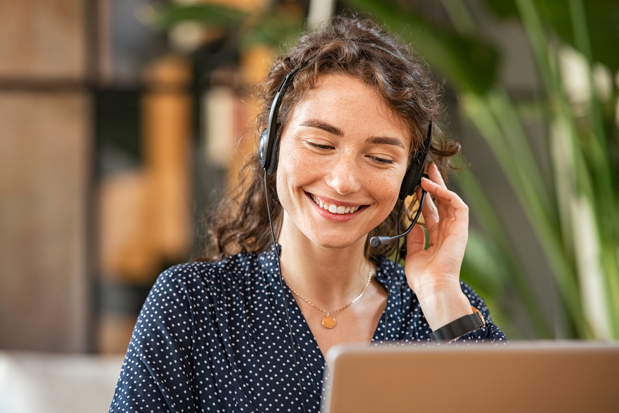 Woman using headset office equipment to carry out a phone conversation. 