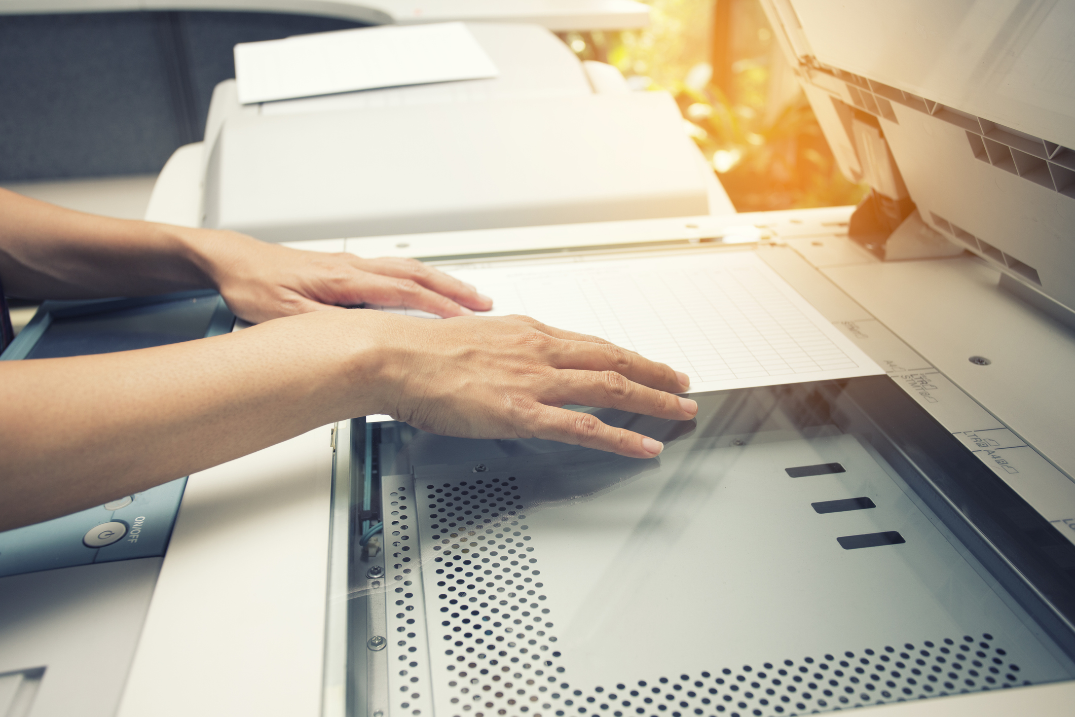 Closeup of a person placing a sheet of paper on a copy machine